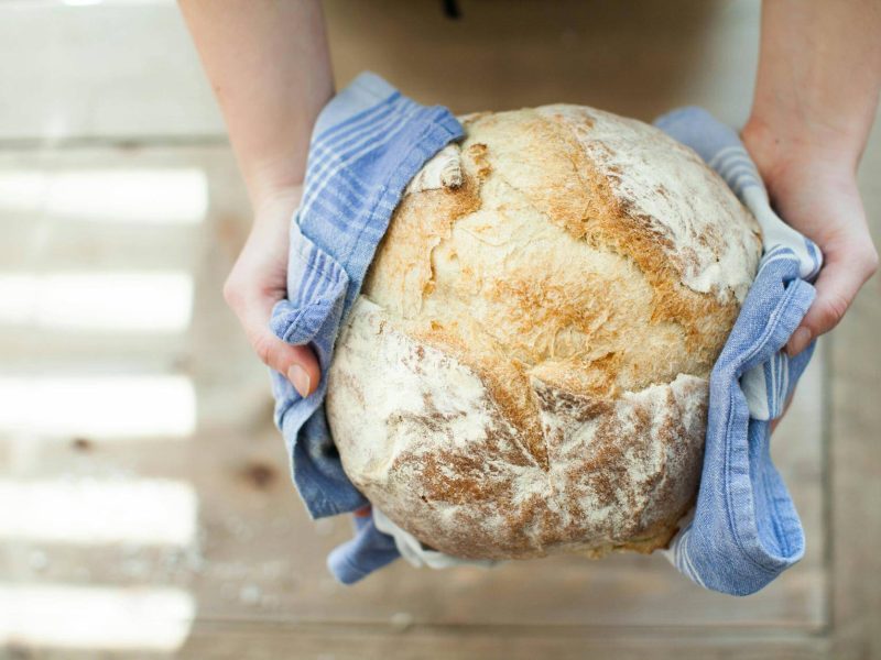 person holding baked pastry covered with towel